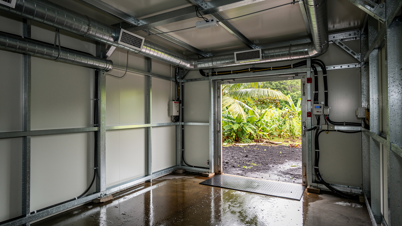 Vue d’un espace modulaire d’urgence avec climatisation et raccordements visibles, accès sécurisé et sol humide tropical en Martinique.